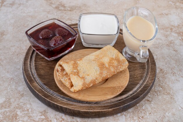 Delicious crepes with sour cream and strawberry jam