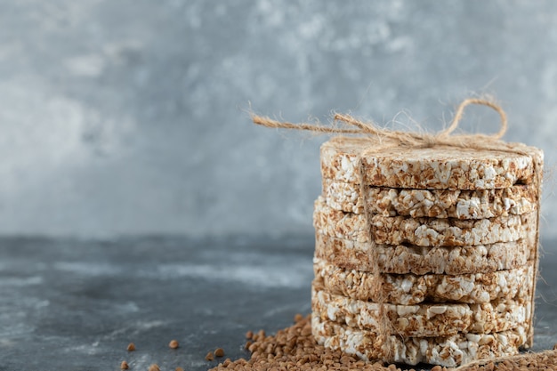 Delicious crispbread and raw buckwheat on marble surface