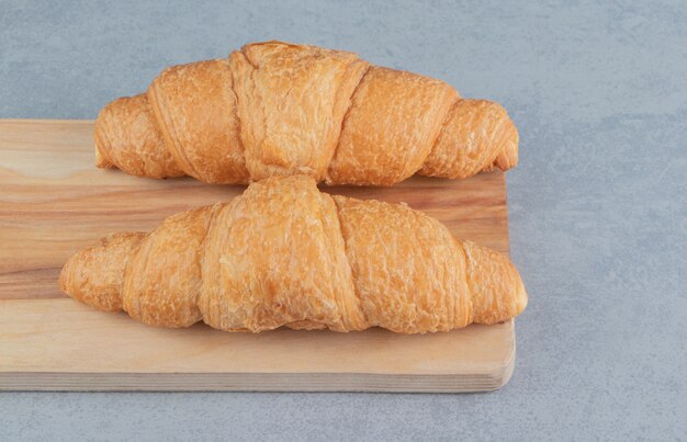 Delicious croissant on the board , on the marble background . High qualityboard photo