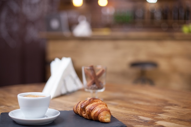 Foto gratuita delizioso croissant servito con una calda tazza di caffè. caffetteria d'epoca. appena sfornato.