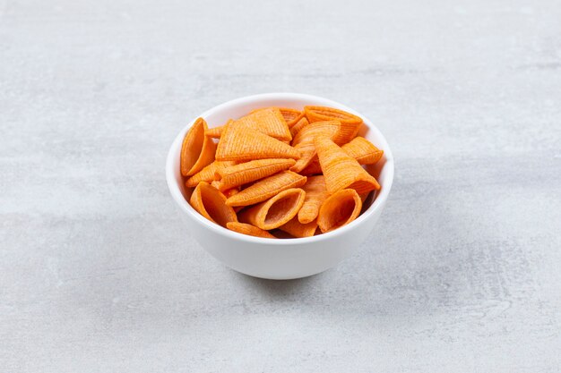 Delicious crunchy chips in white bowl.