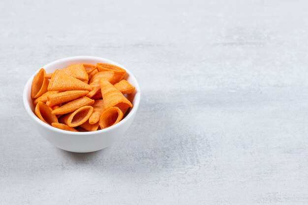 Delicious crunchy chips in white bowl.