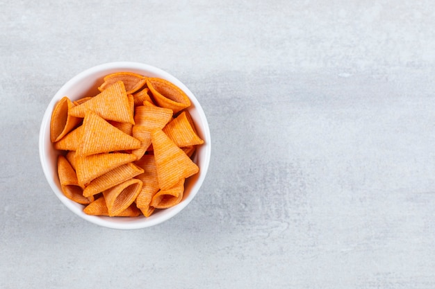 Delicious crunchy chips in white bowl.