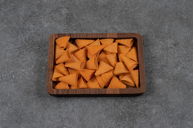 Delicious crunchy chips on wooden plate.