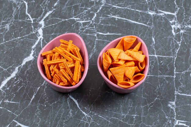 Delicious crunchy stick and triangle chips in pink bowls.