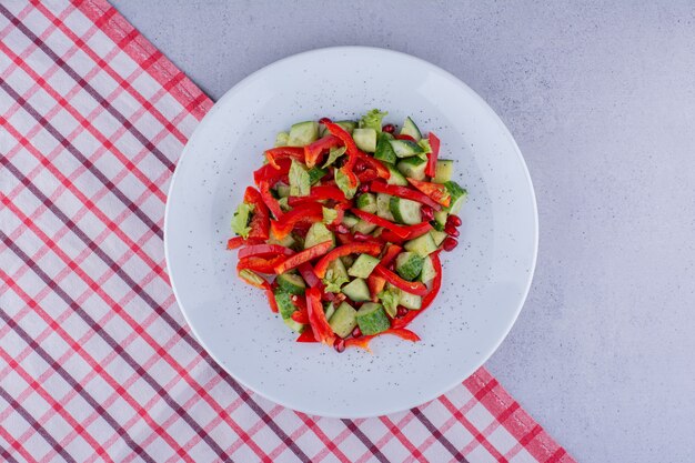 Delicious cucumber, pepper and lettuce salad on a tablecloth on marble background. High quality photo