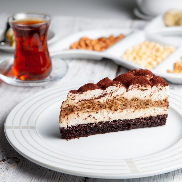 Delicious dessert in a plate with tea, nuts high angle view on a white wooden background