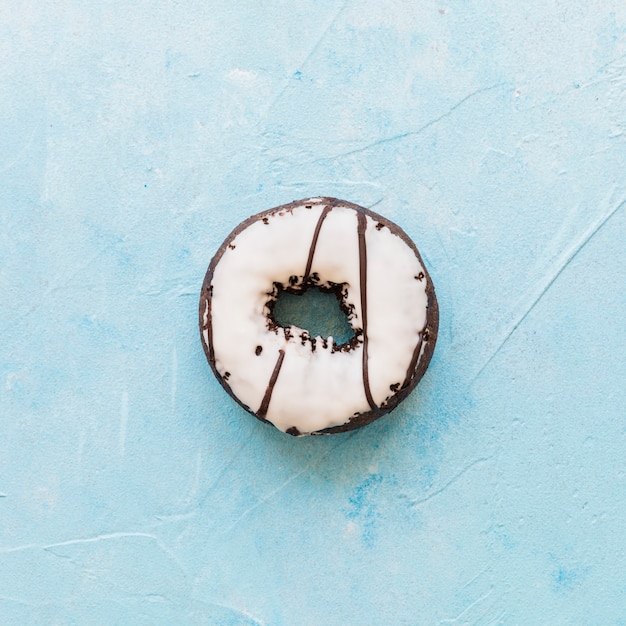 Delicious donut with icing on blue background