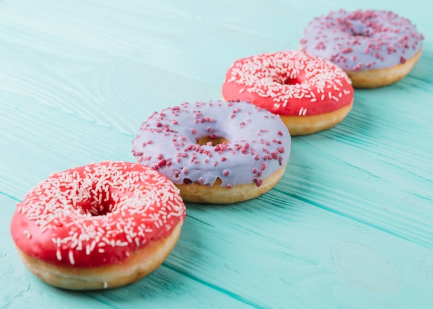 Delicious donuts arranged in a row on wooden table