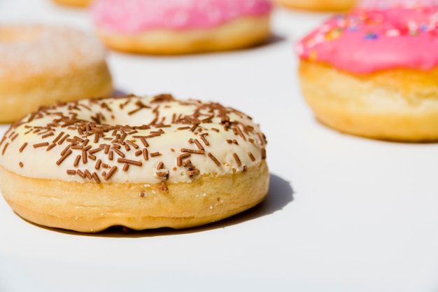 Delicious donuts with sprinkles on white backdrop