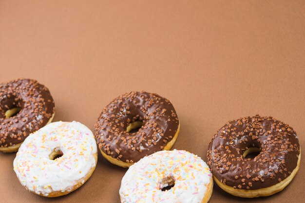 Delicious doughnuts with icing on brown background