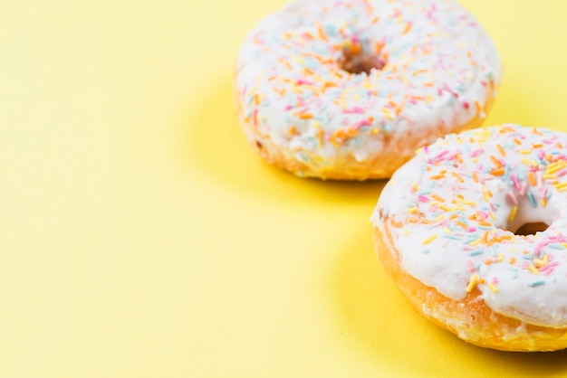 Delicious doughnuts with icing on yellow background