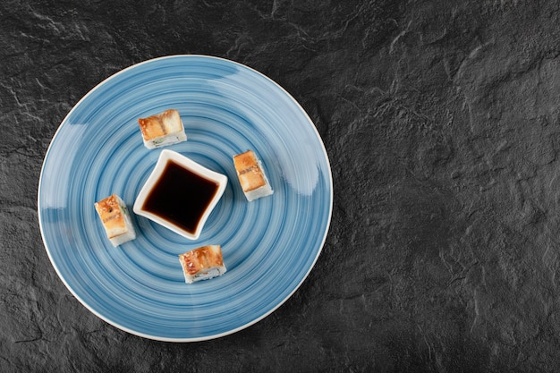 Free photo delicious dragon sushi rolls and soy sauce on blue plate