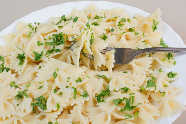 파슬리와 하얀 접시에 포크와 함께 맛있는 farfalle 파스타