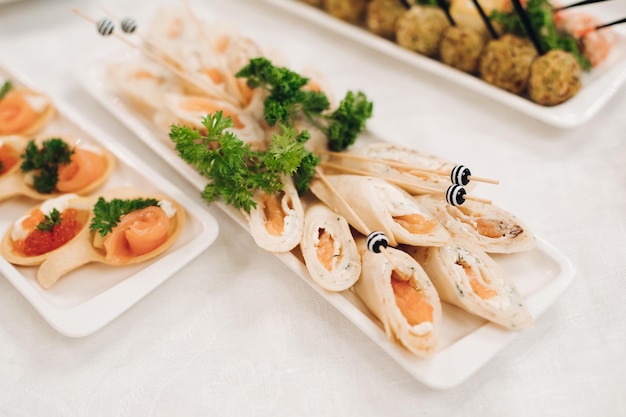 Delicious fish rolls and canape with red caviar served on plates