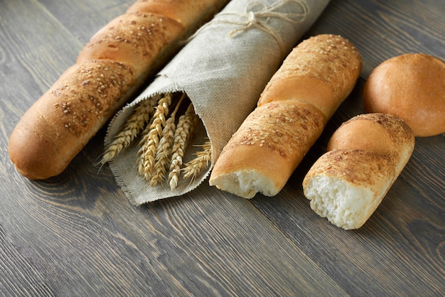 Delicious fresh french baguettes and millets wrapped in craft paper on wooden worktop copyspace store shop market supermarket food retail organic natural recipe eating concept.