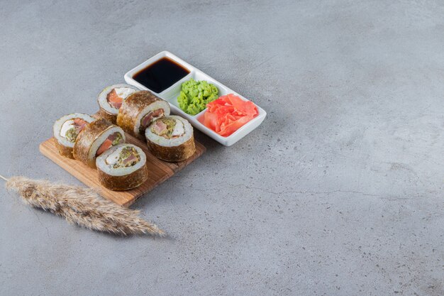 Delicious fresh sushi rolls with soy sauce on wooden board. 