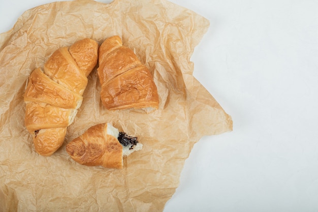 Delicious fresh two croissants on a parchment paper . 