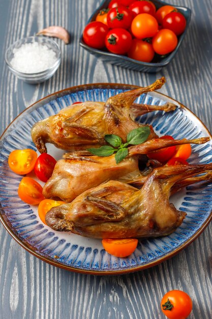 Delicious fried quail with herbs and cherry tomatoes.