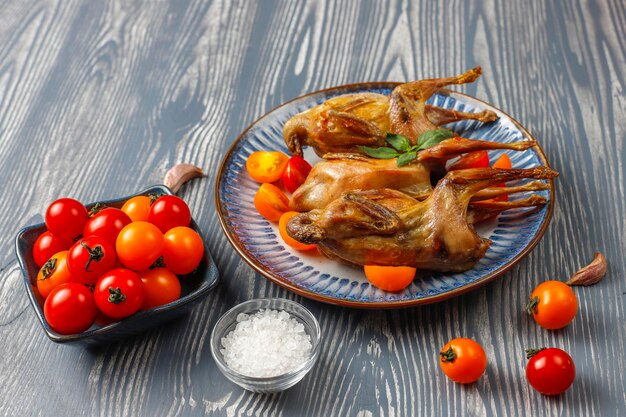 Delicious fried quail with herbs and cherry tomatoes.