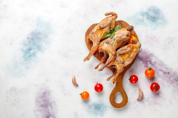 Delicious fried quail with herbs and cherry tomatoes.