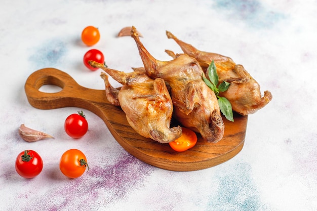 Delicious fried quail with herbs and cherry tomatoes.