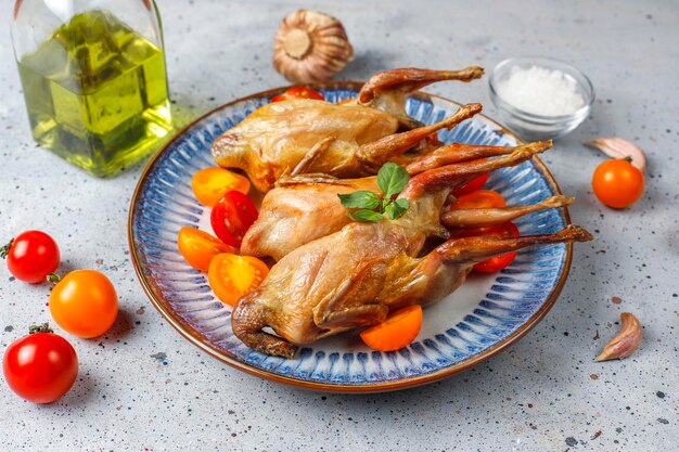 Delicious fried quail with herbs and cherry tomatoes.