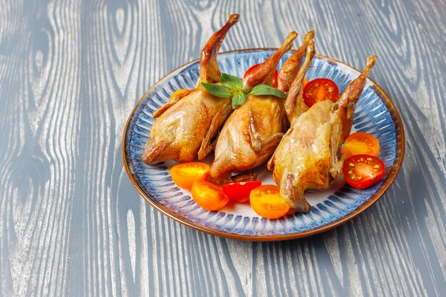 Delicious fried quail with herbs and cherry tomatoes.