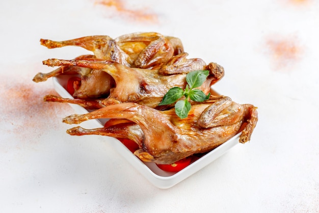 Free photo delicious fried quail with herbs and cherry tomatoes.