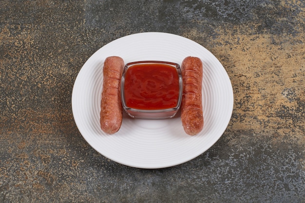 Free photo delicious fried sausages and ketchup on white plate.