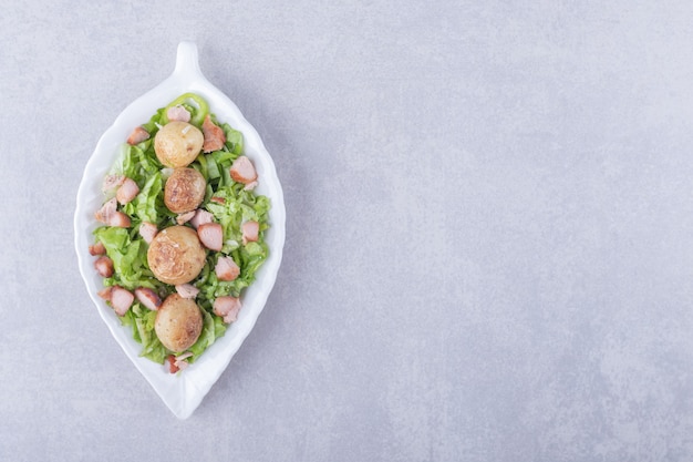 Delicious fried sausages and lettuce in white bowl.