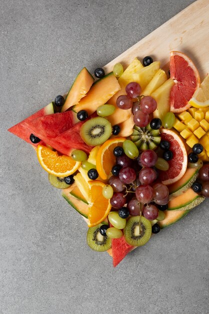 Delicious fruits on wooden board top view