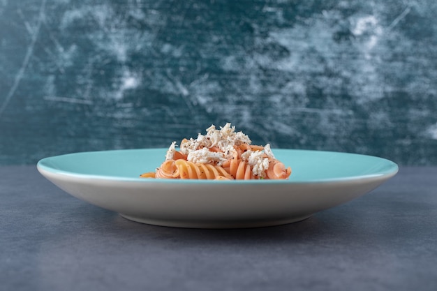 Free photo delicious fusilli pasta and carrot on blue plate.