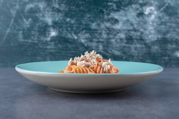 Вкусные макароны и морковь фузилли на синей тарелке.