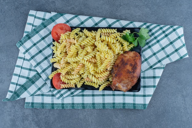 Delicious fusilli with chicken on dark plate. 