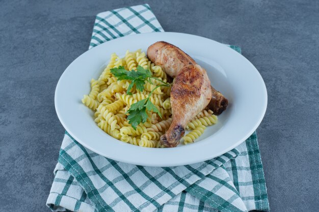 Delicious fusilli with chicken legs on white plate. 