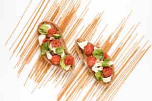 Free photo delicious garnish bruschetta and raw spaghetti pasta over white backdrop