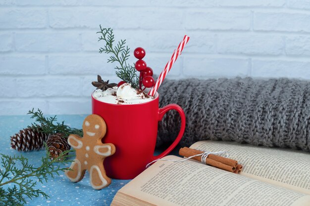 Delicious gingerbread cookie, book and red cup of coffee on blue