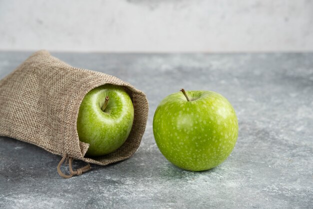 Delicious green apples out of burlap on marble table.
