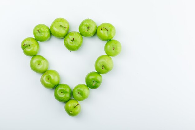 Delicious green plums on a white wall. top view.