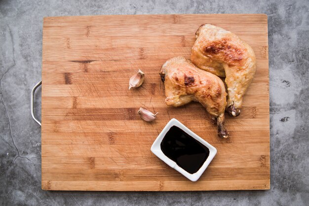 Delicious grilled chicken legs with soy sauce and garlic on cutting board