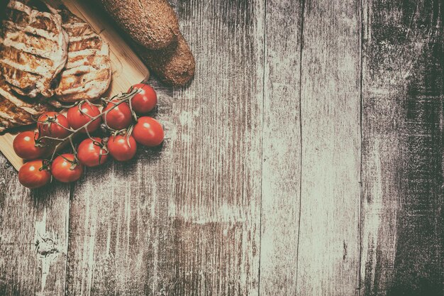 Delicious grilled chicken on wooden board next to healthy bread, tomatoes and salad. Healthy lifestyle and eating