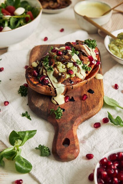 Delicious healthy baked sweet potato with guacamole and mushrooms on a wooden plate on a white table