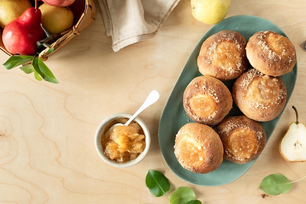 Free photo delicious homemade buns with jam and fresh pears on a wooden background mini pies cooking recipe