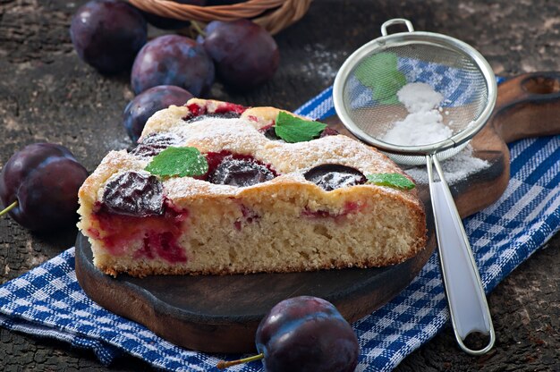 Delicious homemade cake with plums on a wooden