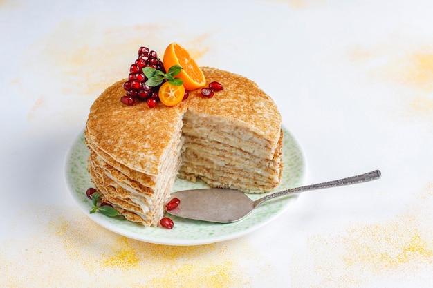 Delicious homemade crepe cake decorated with pomegranate seeds and mandarins.