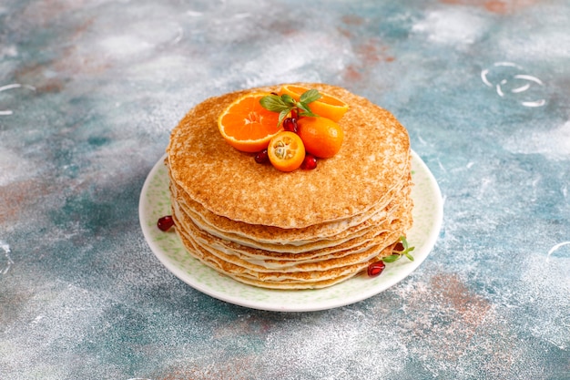 Delicious homemade crepe cake decorated with pomegranate seeds and mandarins.