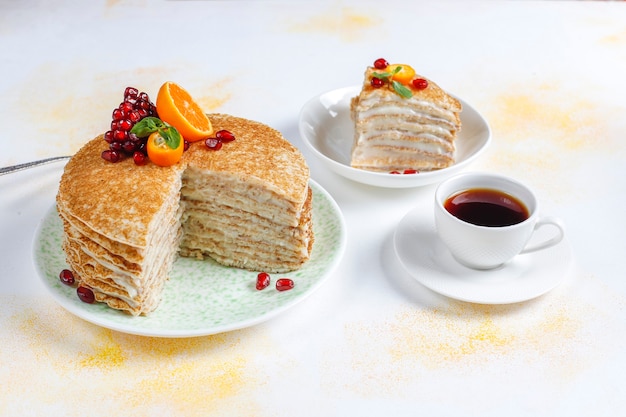 Delicious homemade crepe cake decorated with pomegranate seeds and mandarins.