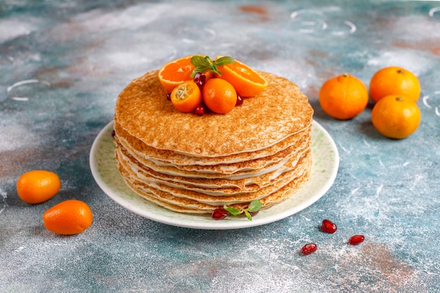 Deliziosa torta di crepe fatta in casa decorata con semi di melograno e mandarini.