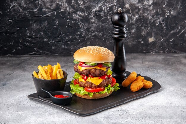 Delicious homemade sandwich and fork ketchup fries on black board on gray isolated surface